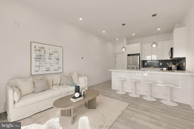 living area featuring recessed lighting, light wood-type flooring, and baseboards