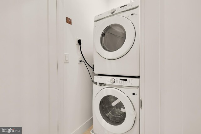 laundry area with baseboards, laundry area, and stacked washer / dryer