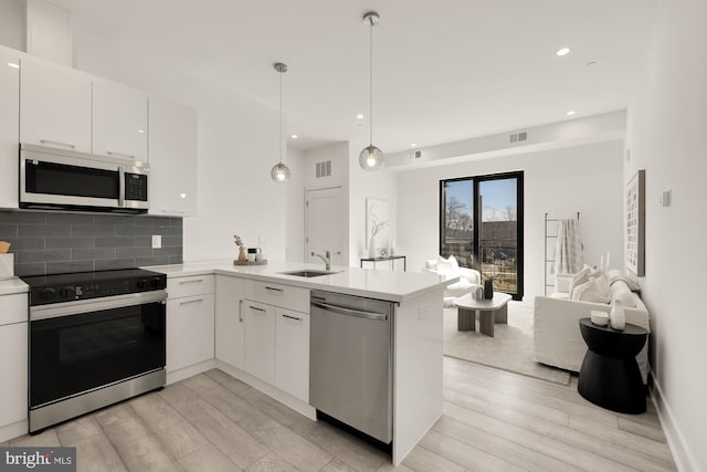 kitchen featuring visible vents, dishwasher, range with electric stovetop, a peninsula, and a sink