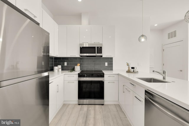 kitchen featuring visible vents, a sink, decorative backsplash, light countertops, and appliances with stainless steel finishes