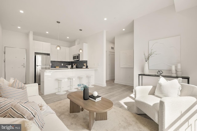 living area featuring recessed lighting, light wood-type flooring, and baseboards