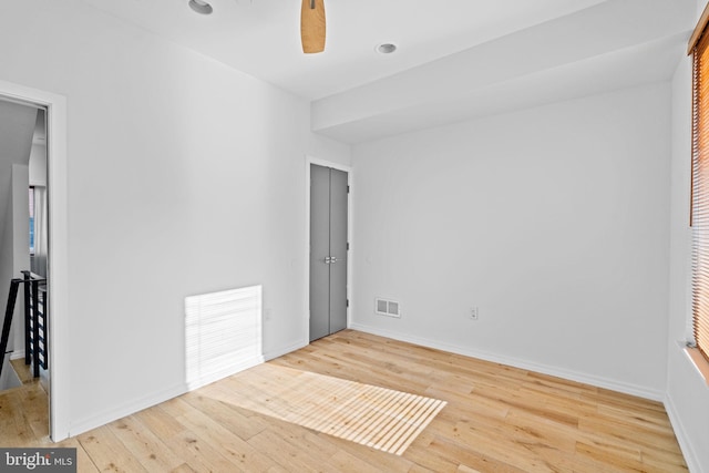 unfurnished room with a ceiling fan, visible vents, baseboards, and hardwood / wood-style flooring