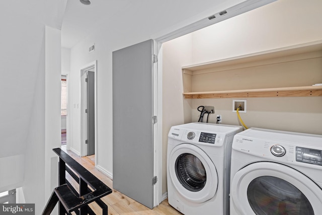 laundry area featuring laundry area, washing machine and dryer, visible vents, and light wood-style floors