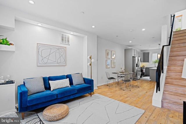 living room with baseboards, visible vents, stairs, light wood-type flooring, and recessed lighting