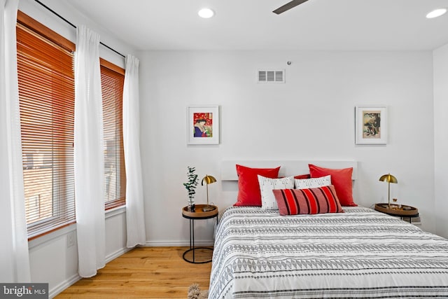 bedroom with baseboards, light wood finished floors, visible vents, and recessed lighting