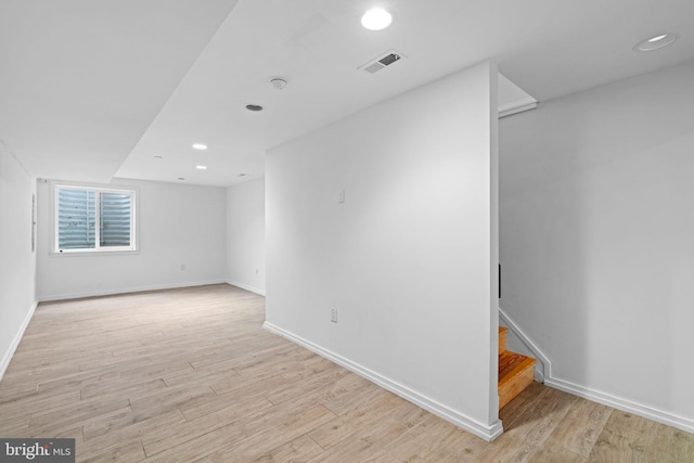 unfurnished room featuring baseboards, visible vents, light wood finished floors, and stairs