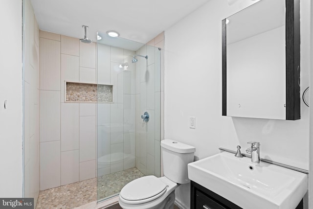 full bath with tiled shower, vanity, and toilet