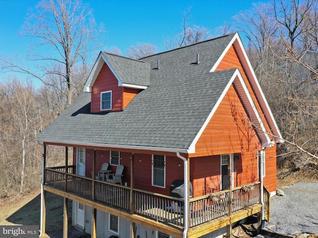 view of front of home with a deck, driveway, and a shingled roof