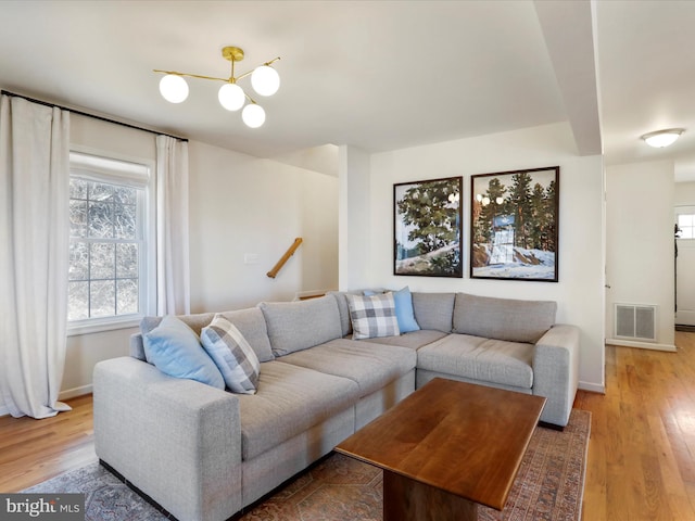 living room with wood finished floors, visible vents, and baseboards