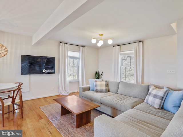 living area with beamed ceiling, baseboards, light wood-style floors, and a healthy amount of sunlight