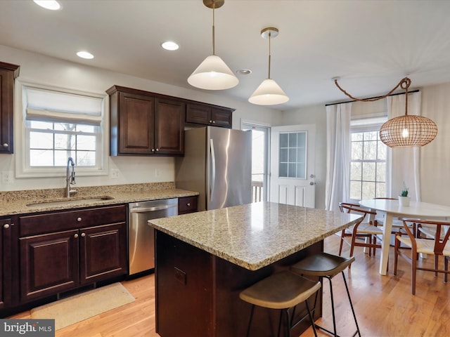 kitchen featuring light stone countertops, visible vents, light wood-style flooring, a sink, and appliances with stainless steel finishes