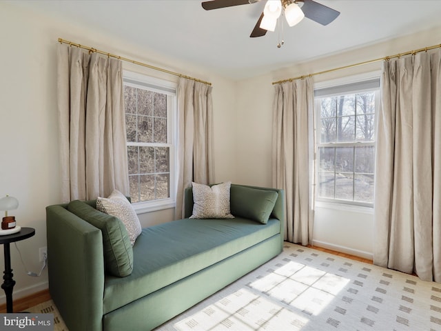 living area with a ceiling fan and baseboards