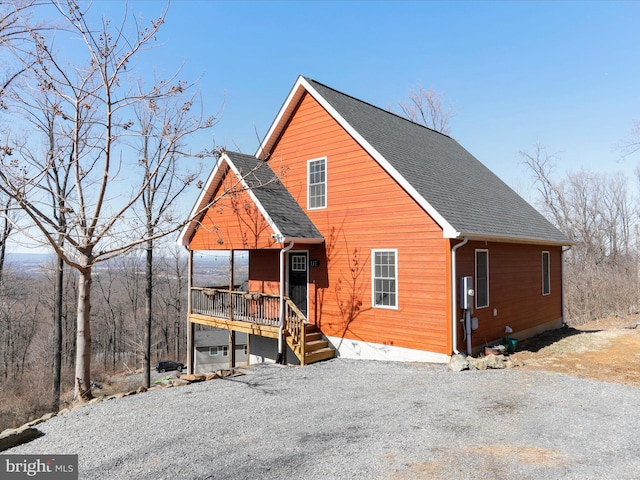 chalet / cabin with gravel driveway, roof with shingles, and crawl space