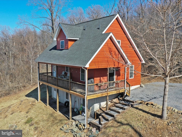 view of front of house with a wooden deck, a front yard, driveway, and a shingled roof