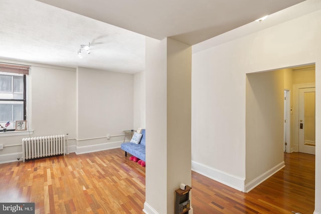 interior space featuring baseboards, radiator heating unit, and wood finished floors