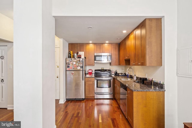 kitchen featuring appliances with stainless steel finishes, dark wood-style flooring, a sink, and brown cabinets