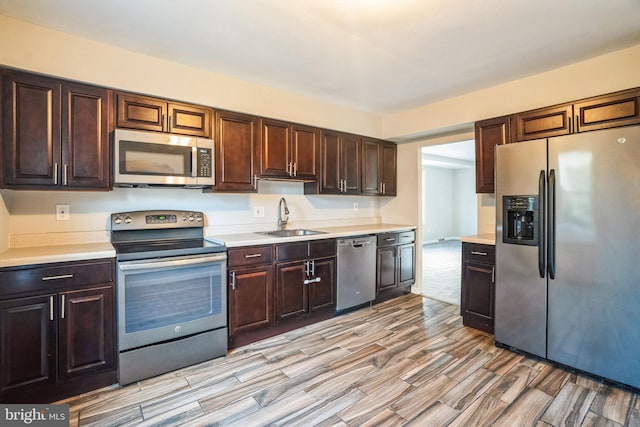 kitchen with stainless steel appliances, light countertops, a sink, and dark brown cabinetry