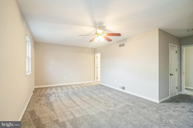 carpeted empty room with a ceiling fan, visible vents, and baseboards