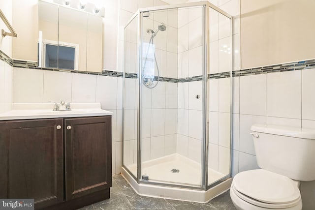 bathroom with toilet, marble finish floor, vanity, a shower stall, and tile walls