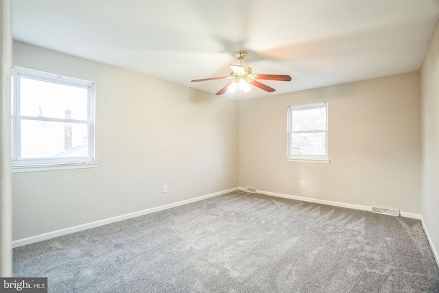 carpeted empty room featuring a ceiling fan, visible vents, and baseboards