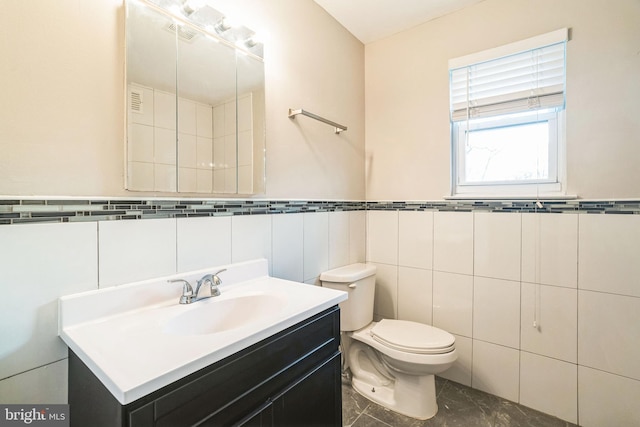 bathroom with toilet, a wainscoted wall, tile walls, and vanity