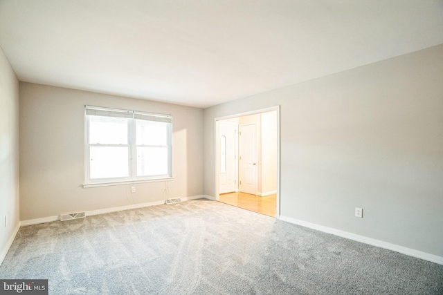 carpeted empty room featuring visible vents and baseboards