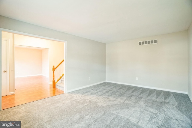 unfurnished room with stairway, carpet, visible vents, and baseboards