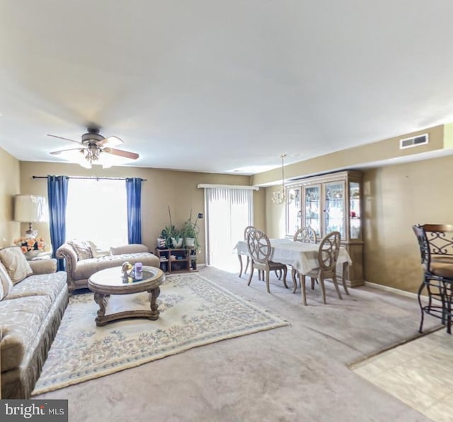 carpeted living area with visible vents, baseboards, and a ceiling fan