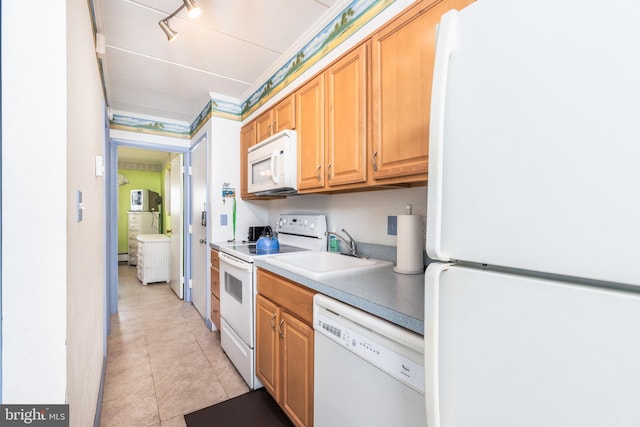 kitchen with a sink, white appliances, light countertops, and light tile patterned floors