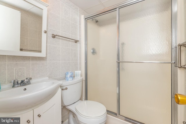 bathroom with vanity, tile walls, toilet, and a shower stall