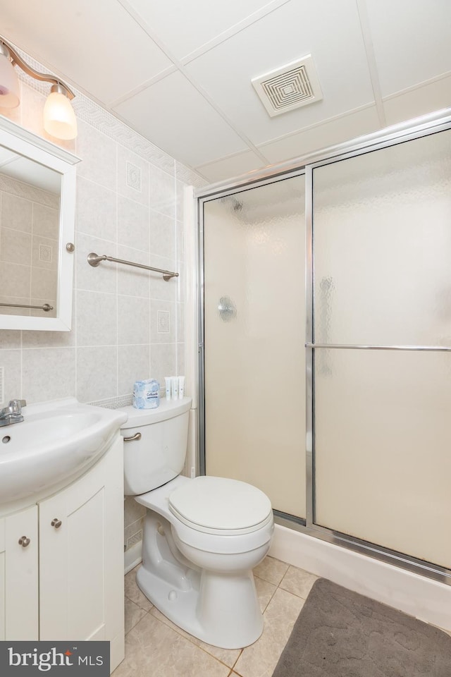 full bath featuring tile patterned flooring, visible vents, toilet, vanity, and tile walls