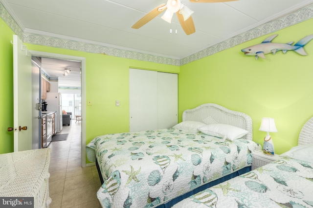 tiled bedroom with a closet, a ceiling fan, crown molding, and freestanding refrigerator