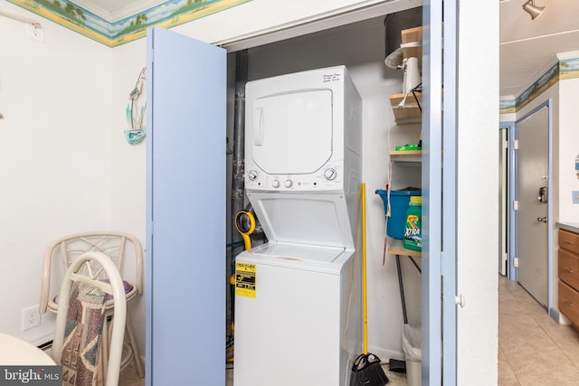 laundry area with light tile patterned flooring, laundry area, and stacked washing maching and dryer