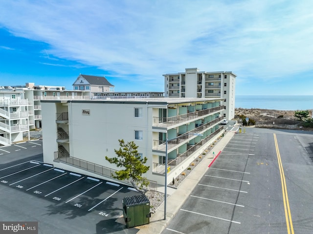 view of building exterior featuring uncovered parking and a water view