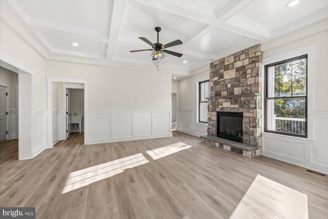 unfurnished living room featuring beam ceiling, visible vents, a stone fireplace, and wood finished floors