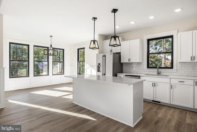 kitchen with appliances with stainless steel finishes, a kitchen island, a sink, and dark wood finished floors