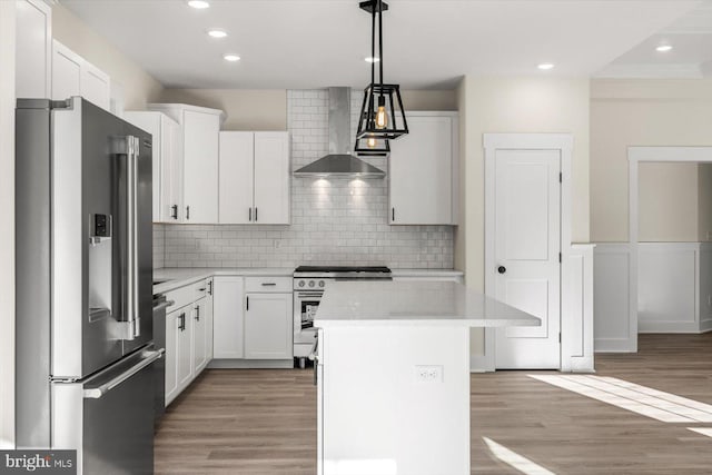 kitchen with high end appliances, a kitchen island, wall chimney range hood, and light wood-style flooring