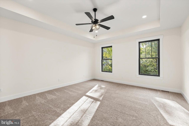 unfurnished room featuring ceiling fan, recessed lighting, carpet floors, baseboards, and a raised ceiling