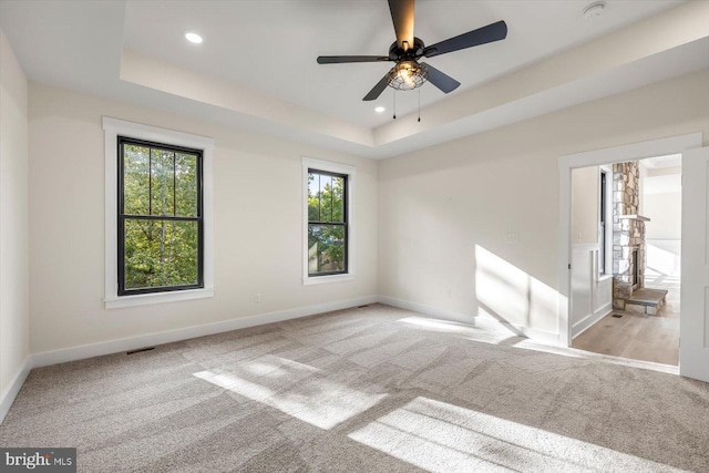 carpeted spare room featuring recessed lighting, a raised ceiling, visible vents, ceiling fan, and baseboards