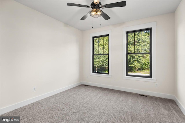 carpeted empty room featuring ceiling fan, visible vents, and baseboards