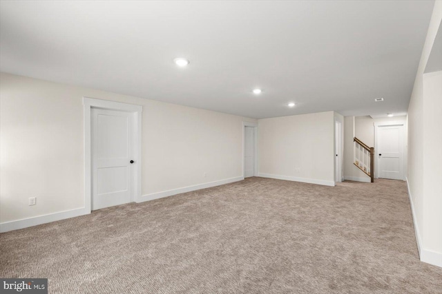 below grade area featuring recessed lighting, light carpet, stairway, and baseboards