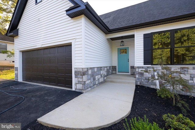 view of exterior entry featuring stone siding and roof with shingles