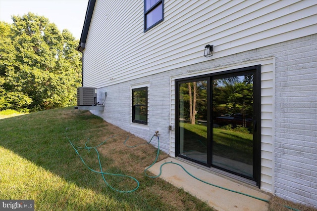 view of property exterior featuring central AC unit, a lawn, and brick siding