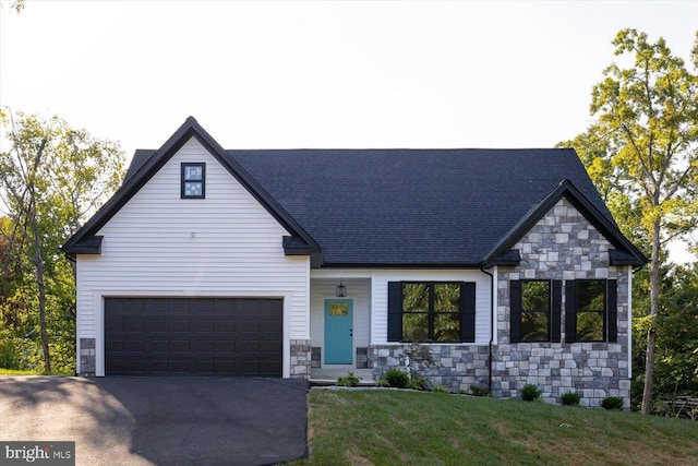 view of front of home featuring aphalt driveway, a front yard, stone siding, and roof with shingles