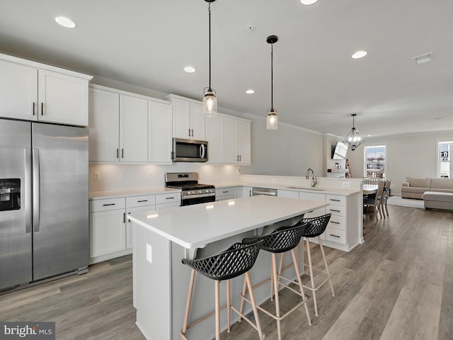 kitchen with visible vents, appliances with stainless steel finishes, open floor plan, a peninsula, and light wood-type flooring