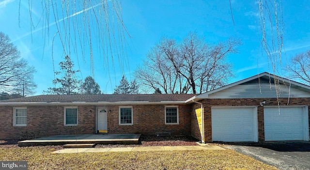 single story home with a garage, brick siding, a front yard, and aphalt driveway