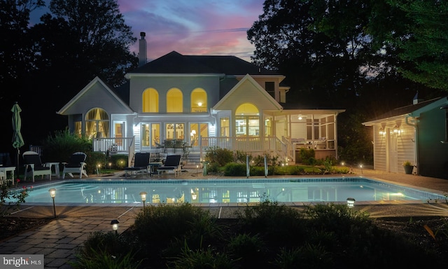 rear view of house featuring a deck, a patio, french doors, and an outdoor pool