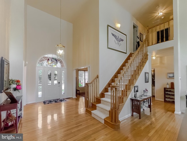 entrance foyer featuring stairs, wood finished floors, baseboards, and a towering ceiling