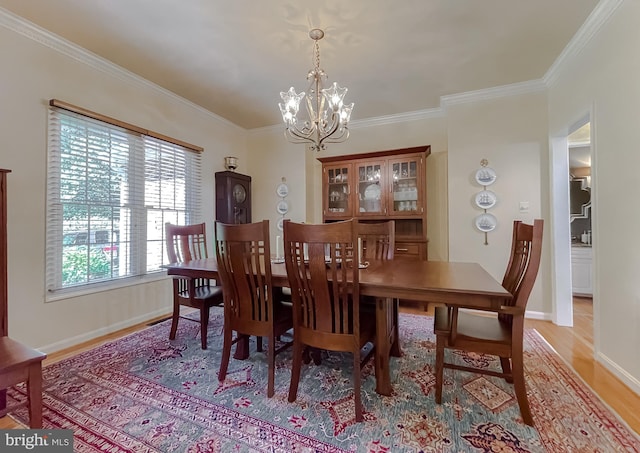 dining space featuring baseboards, a chandelier, crown molding, and light wood finished floors