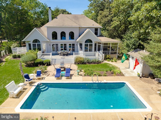 rear view of property featuring fence, a lawn, a sunroom, a patio area, and an outdoor pool